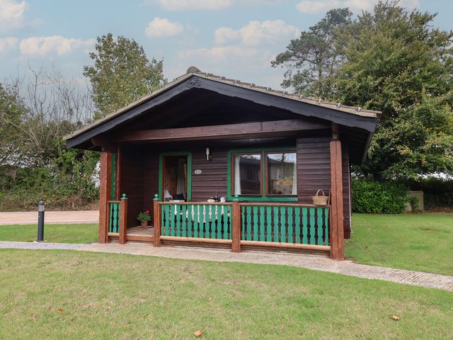 A wooden cabin with green railing and a pathway at 10 Pinewood Retreat in Pinewood