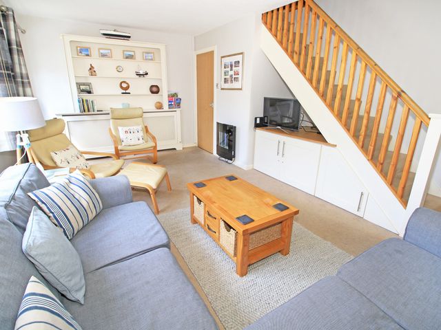 A living room with blue sofas wooden coffee table and built in shelves at Green Cottage in Borth-Y-Gest