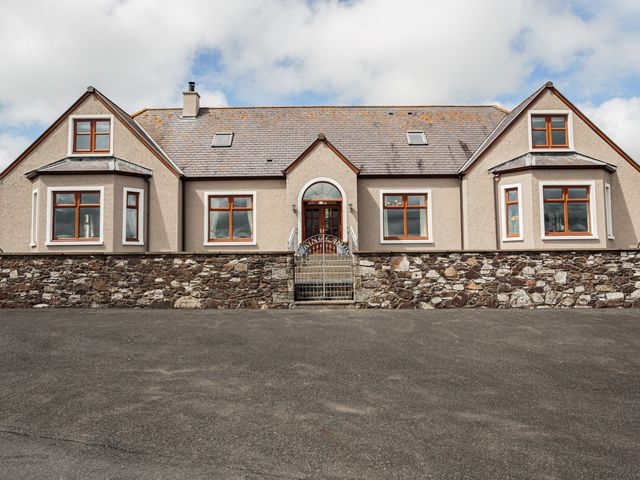 A stone and stucco house with a central gate and wooden framed windows at Kringlands in Kirkcolm