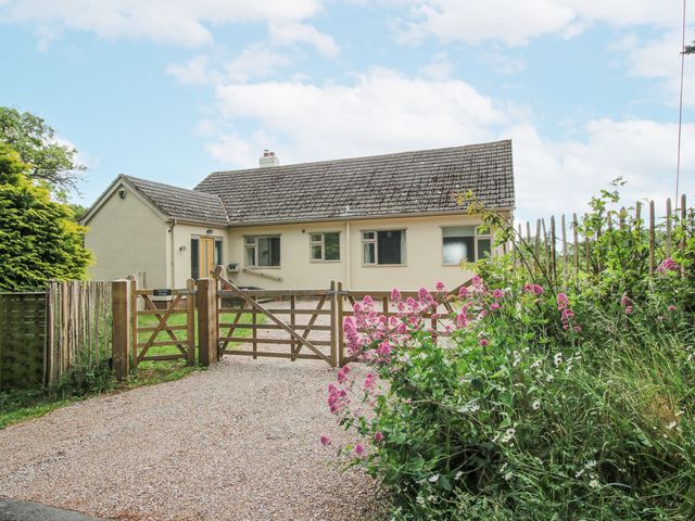 A house viewed from the front with a gate and flowers at Pear Tree Cottage in Church Pulverbatch near Dorrington