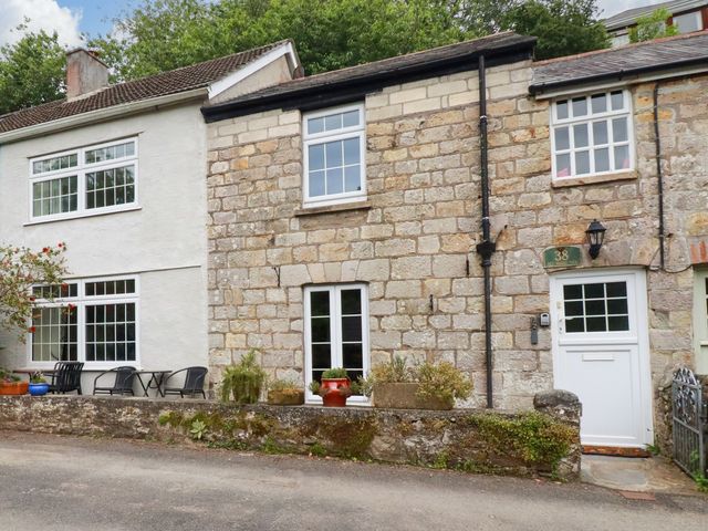 A residential exterior with stone wall and windows at Vi’s Valley View in Pentewan