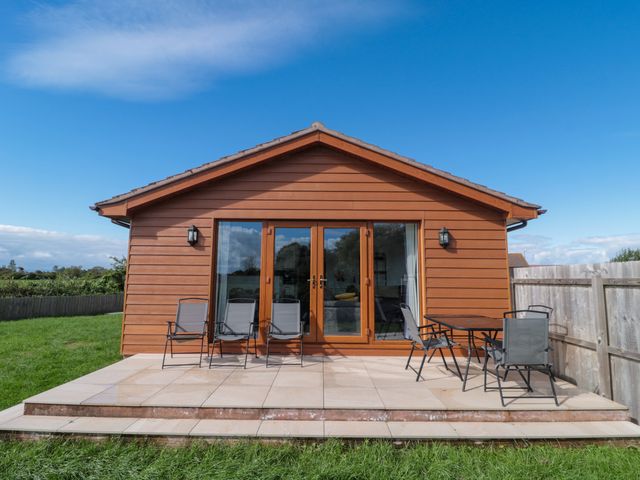 An outdoor patio with chairs and a table at Delphine Lodge, Meadow View Lodges, Brean