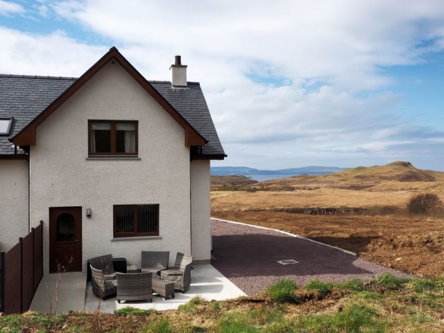 An outdoor view of a house with seating area at Falls Cottage in Uig