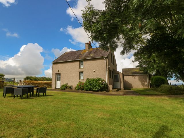 A house with a lawn and outdoor chairs under a tree at Garreg Lwyd Farm Morfa Nefyn near Nefyn