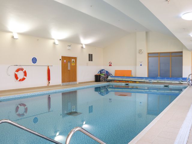An indoor swimming pool with handrails a lifebuoy and safety equipment on the wall at Flat 33 - Marine Court in Littlehampton