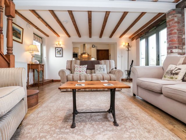 A living room with sofas a wooden coffee table and exposed ceiling beams at The Cart House in Skipsea