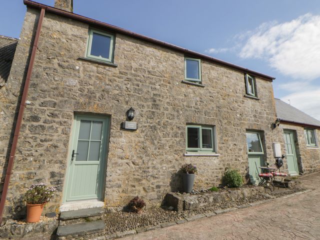 A building exterior with a stone wall and green door at Swallows Retreat in Tenby