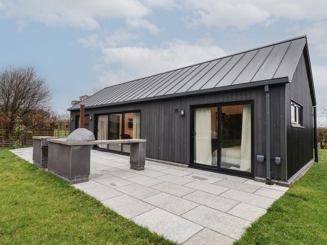 A modern black house with a gray metal roof and a patio area with a built-in outdoor oven at Wren in Huggate near Bishop Wilton