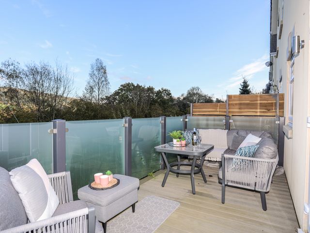 An outdoor balcony with seating furniture a table and frosted glass panels at 3 Trem Y Dolydd Dolgarrog near Llanrwst