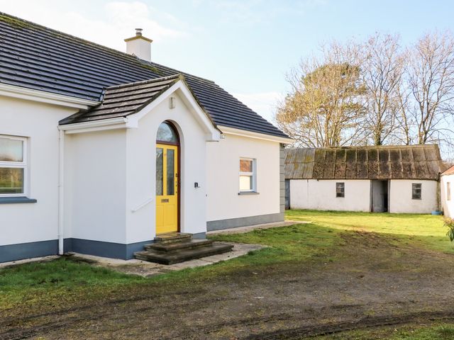 A white house with a yellow front door and steps leading to it with a detached shed in the background at 17 Buninver Road Gortin