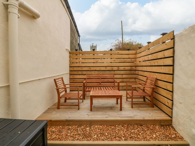 An outdoor seating area with wooden chairs and a table on a wooden deck surrounded by wooden slat fencing at Glanffrwd - Nefyn in Nefyn