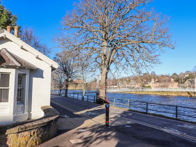A tree by a river with a pathway and building at Porter's Lodge in Inverness