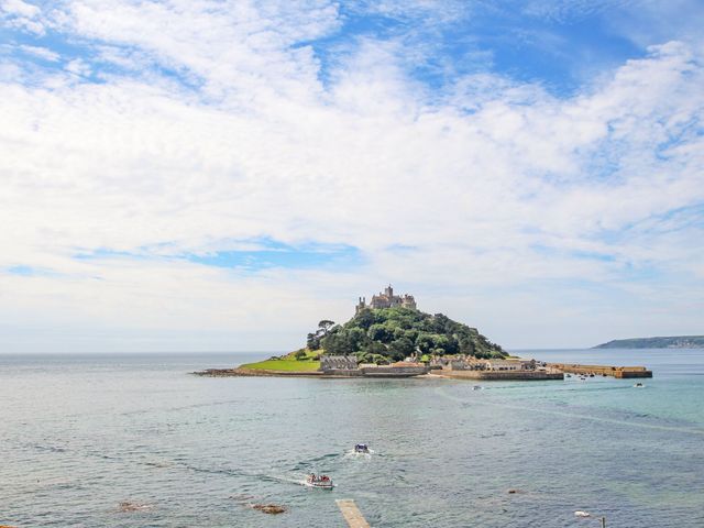 An island with a castle and boats in the water at Meledor in Marazion