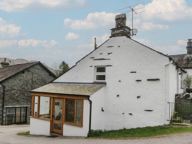 An outdoor view of a cottage with a glass extension at Woodloft Cottage Elterwater near Chapel Stile