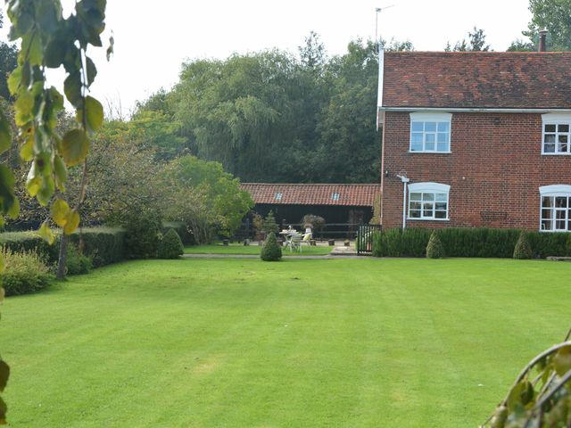 A garden with lawn and trimmed bushes next to a brick house at Rookyards in Spexhall Near Halesworth