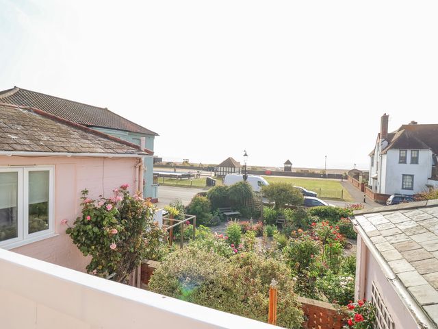 A garden with flowering bushes and parked cars near houses by the seaside at Crabbe House in Aldeburgh