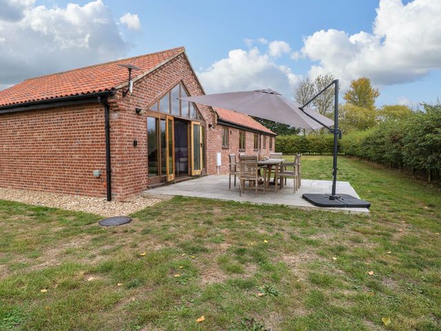 A garden with outdoor seating and a parasol at The Mulberry, nr Bungay
