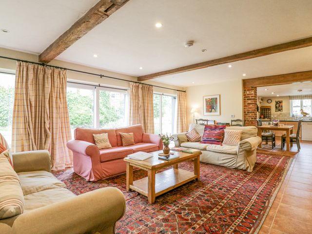 A living room with sofas a wooden coffee table and a dining area in the background at The Cart House Sudbourne Near Orford