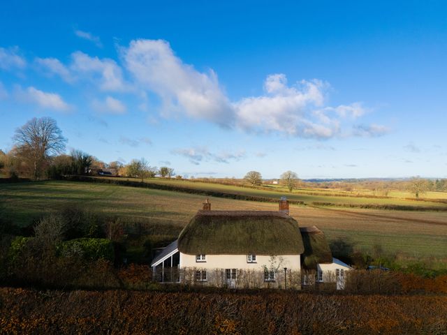 A cottage with a thatched roof in a field at Rose Cottage Okehampton