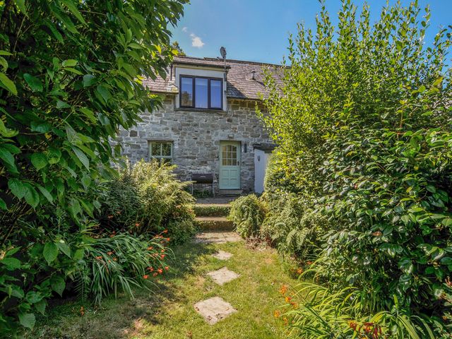 A stone building with a pathway and plants at The Mews in Blisland