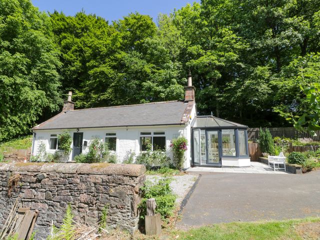 A house with a conservatory and garden area at Nithbank Cottage