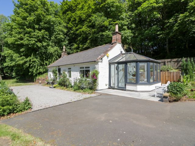 A cottage with a conservatory and parking area at Nithbank Cottage in 