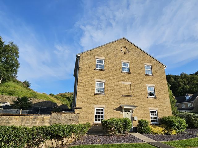 A house with windows and a door surrounded by bushes at The Milne in Todmorden