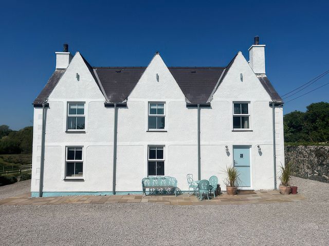 A house with a front door and patio furniture at Cae Du Dwyran near Niwbwrch (Newborough)