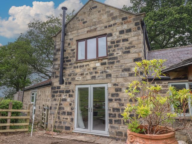 An outdoor view of a stone cottage with a door and windows at Cliffe House Cottage