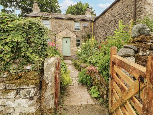 A stone cottage with a green door and garden path at White House in Shap