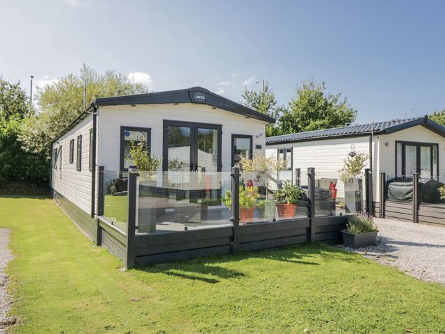 A mobile home with a porch and plants at Lilac Lodge Carnforth