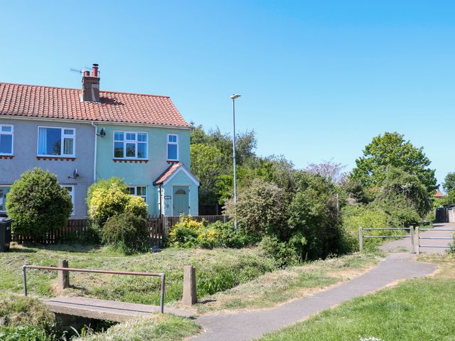 A semi detached house with a small garden and a path with a footbridge in front of it at Beck View in Sheringham