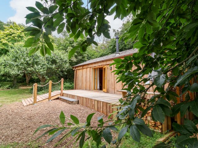 A wooden cabin with a deck and entrance at Brambly Cabin in Crediton