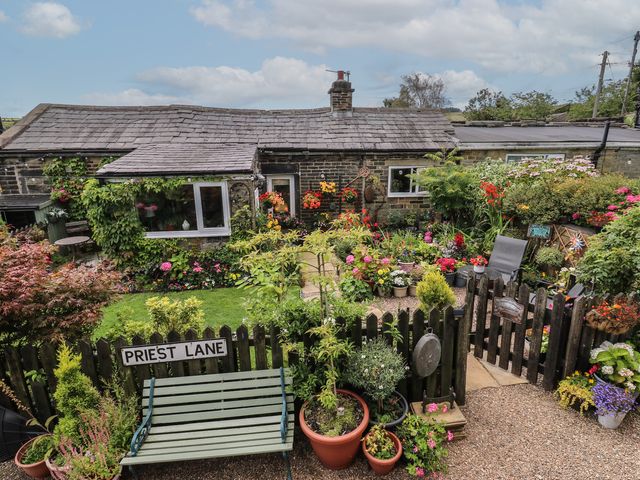 A garden with a house and flowers at Prospect Cottage in Ripponden