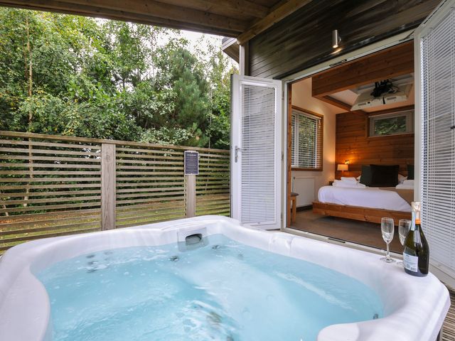 A hot tub with outdoor decking and a bed visible through a sliding door at 3 Southern Place Dobwalls