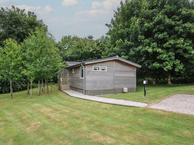 A wooden cabin surrounded by grass and trees at 24 Meadow Retreat Dobwalls