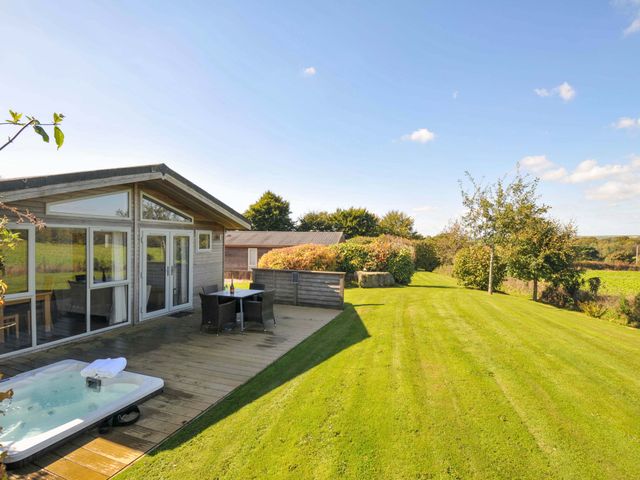 A garden with a deck, hot tub, table, and chairs at 3 Horizon View in Dobwalls