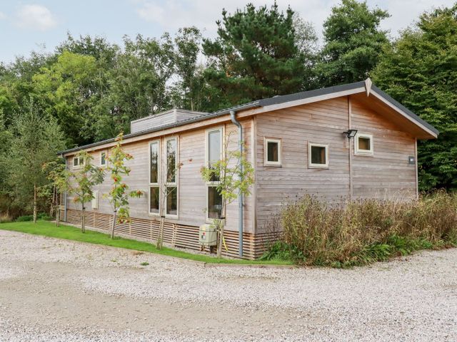 A wooden single-story building surrounded by trees and gravel path at 9 Meadow Retreat in Dobwalls