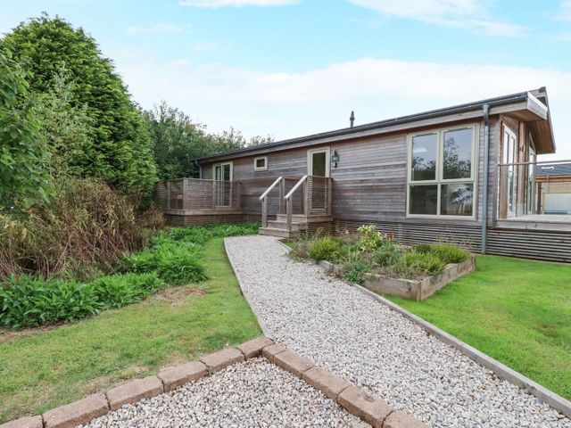 A wooden house with a gravel pathway and garden at 2 Meadow Retreat in Dobwalls
