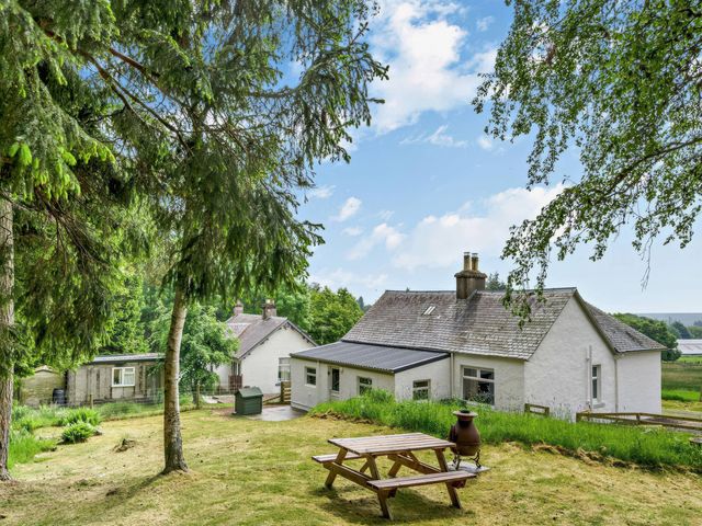 An outdoor area with a house, table, and trees at Upper Hillside Cottage in Blairgowrie