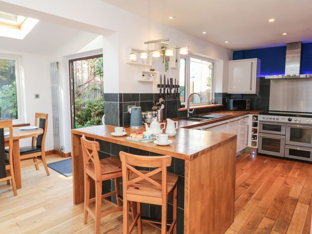 A kitchen with a wooden island, bar stools, a stove, and a dining table near a garden door at Hillsview in Combe Martin