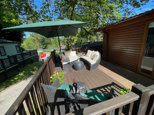 An outdoor space with furniture and an umbrella at Treetops, Beech Hill 13, Fallbarrow Park near Bowness-On-Windermere