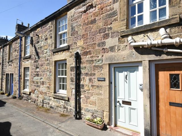 Stone terraced houses with white and brown doors on a narrow street at Sandpiper Alnmouth