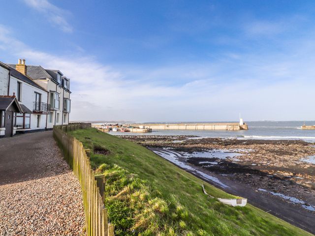 A coastal view with a building and pier at Cuddy's Holm Seahouses