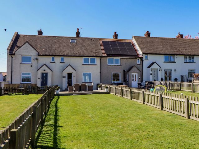 A row of houses with a garden and fences at Dunford Cottage in Bamburgh