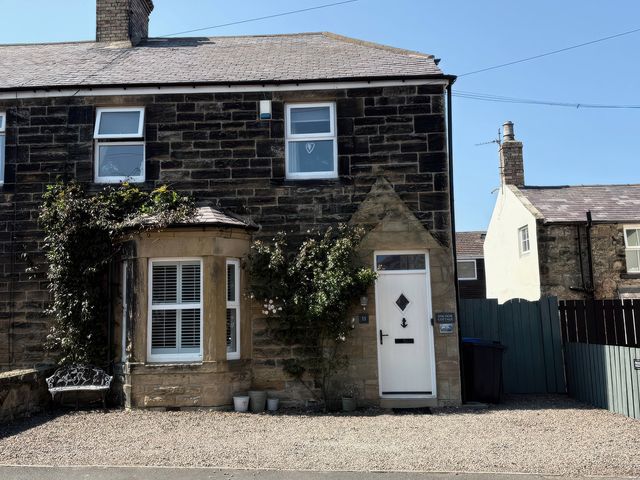 A stone house with a front door and windows at Anchor Cottage in Seahouses