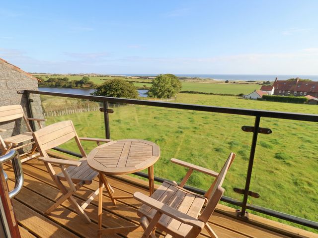 A balcony with a table and chairs overlooking the ocean at Links View in Embleton