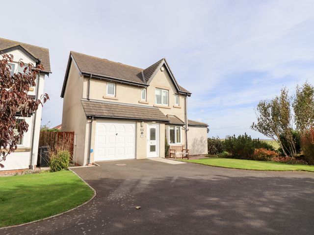 A house with a garage door and garden at Beach View in Seahouses