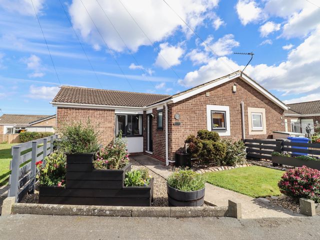 A house with a garden and flower bed at Flora Cottage Beadnell
