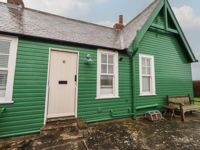 A green house with a door and windows at Armstrong Cottages No6 Bamburgh